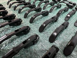 Several rows of black metal mechanical parts are arranged on a sheet of green bubble wrap.