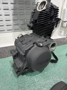 A black motorcycle engine on a green surface.
